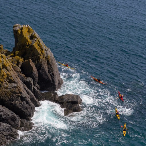 Kayakers pass the Colt, Cadgwith, Cornwall.